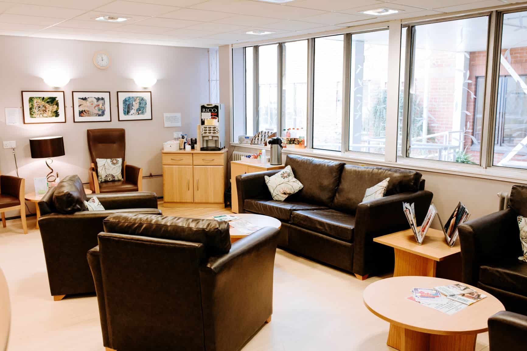 An empty room at the Cancer Care centre in York - the room is filled with sofas and side tables. There are big windows along the right hand side of the room.