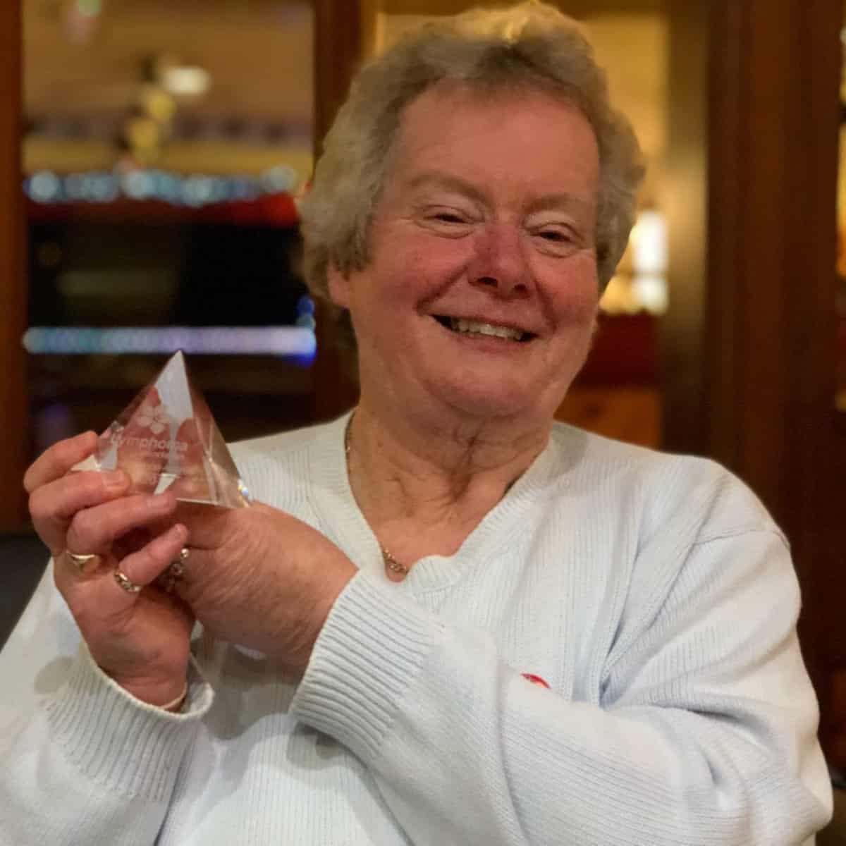 Carol Miller, founder of York Haematology Support group and Acute Myeloid Leukaemia survivor smiling and holding an award from the Lymphoma Association.